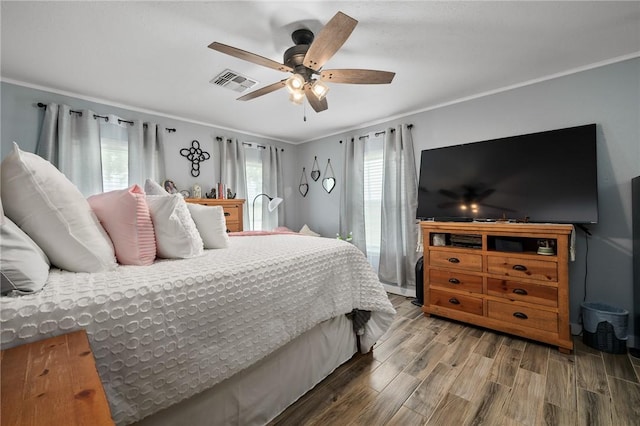 bedroom with hardwood / wood-style floors, ceiling fan, and crown molding