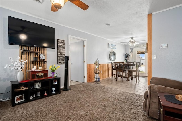 living room featuring ceiling fan, crown molding, and carpet