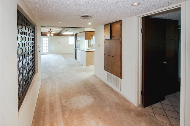 corridor featuring light carpet and a textured ceiling