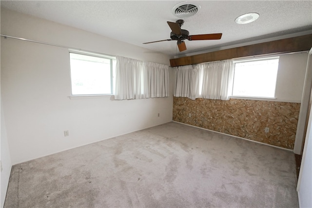 spare room with light carpet, ceiling fan, and a textured ceiling