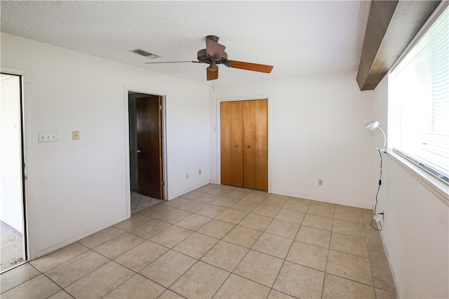 tiled spare room featuring a textured ceiling and ceiling fan