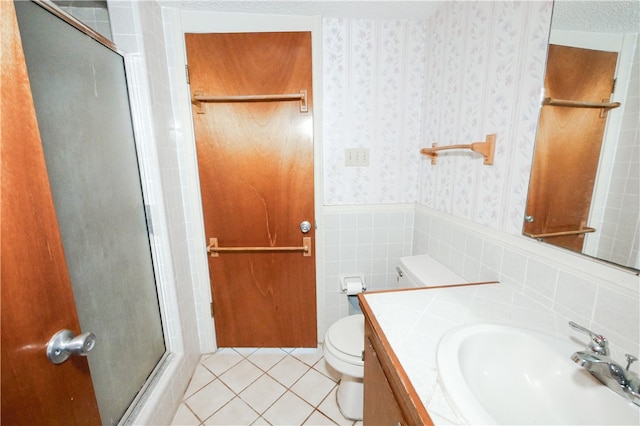 bathroom with toilet, tile walls, tile patterned floors, an enclosed shower, and vanity