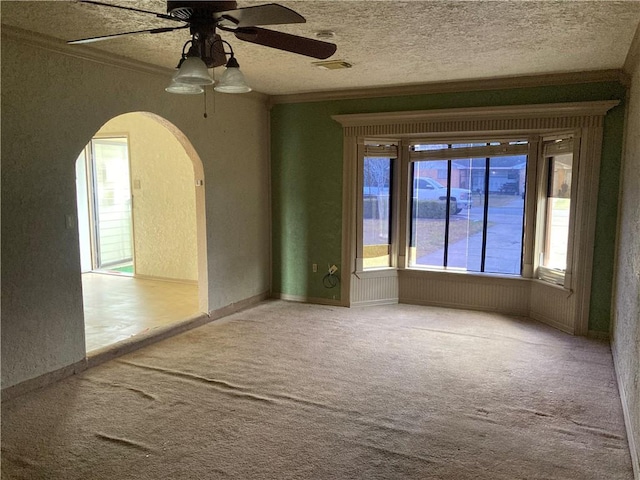 carpeted spare room with arched walkways, visible vents, crown molding, and a textured ceiling