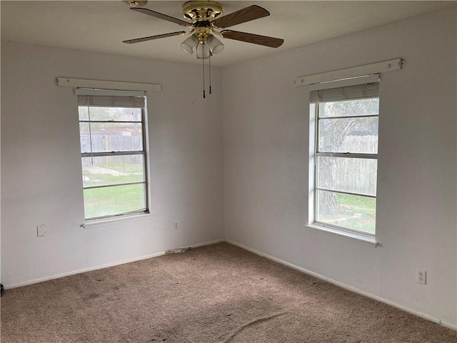 carpeted empty room with baseboards, a ceiling fan, and a wealth of natural light