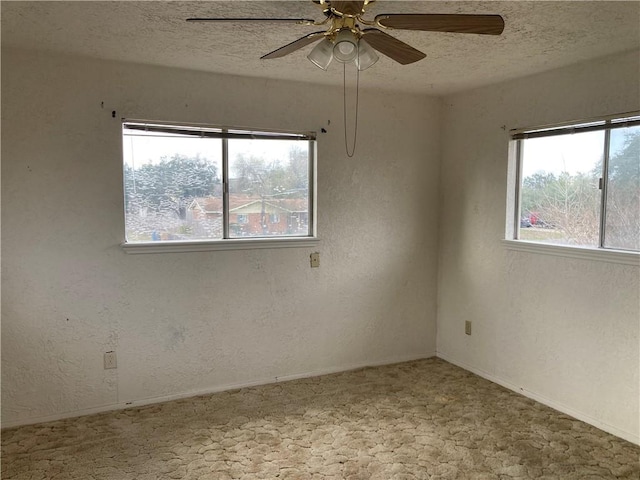 spare room with a textured ceiling, a textured wall, plenty of natural light, and carpet flooring