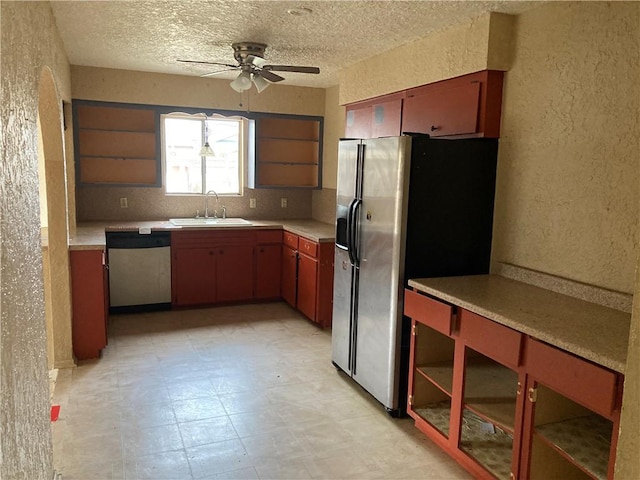 kitchen featuring a textured wall, stainless steel appliances, light floors, open shelves, and a sink