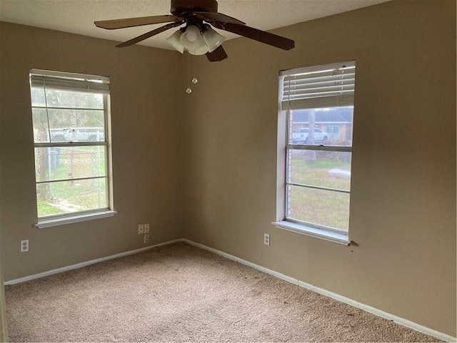 empty room with baseboards, carpet floors, ceiling fan, and a healthy amount of sunlight