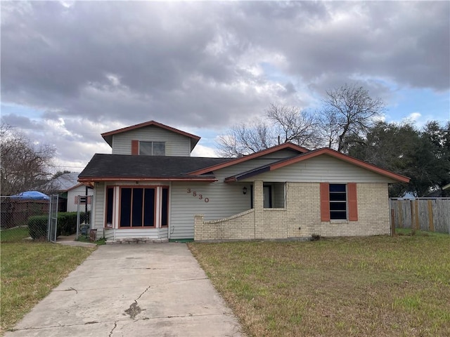 bungalow with a front yard, brick siding, and fence