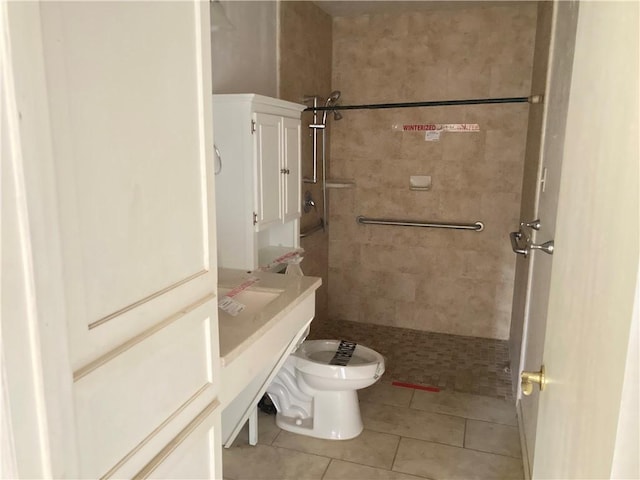 bathroom featuring toilet, tile patterned flooring, and a tile shower