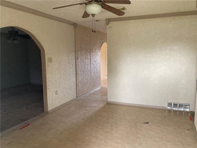 spare room featuring arched walkways, visible vents, ceiling fan, and tile patterned floors