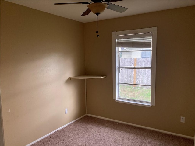 carpeted empty room with a ceiling fan and baseboards