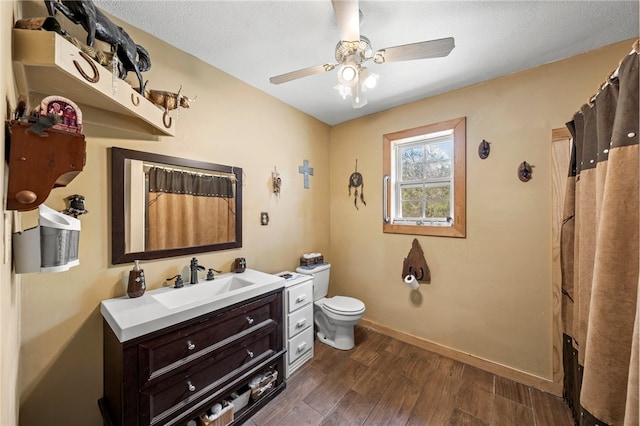 bathroom featuring vanity, a textured ceiling, hardwood / wood-style floors, toilet, and ceiling fan