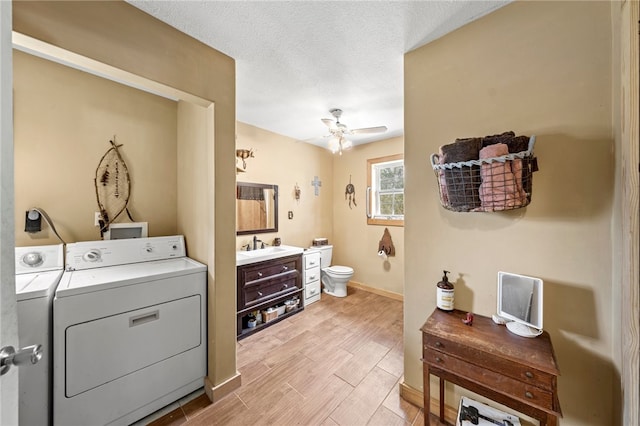 washroom with light hardwood / wood-style floors, sink, ceiling fan, a textured ceiling, and washing machine and dryer