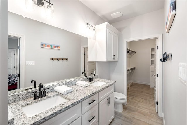 15417 Palmira Ave Unit B, Corpus Christi, TX 78418 - bathroom featuring double vanity, wood finished floors, a walk in closet, toilet, and ensuite bathroom