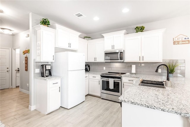 15417 Palmira Ave Unit B, Corpus Christi, TX 78418 - kitchen with stainless steel appliances, a sink, decorative backsplash, light wood-type flooring, and white cabinetry