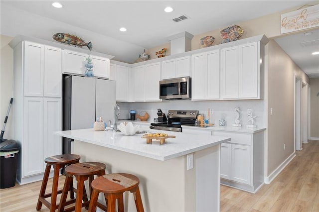268 Flounder Dr, Port Aransas, TX 78373 - kitchen with stainless steel appliances, a kitchen bar, white cabinets, backsplash, and recessed lighting