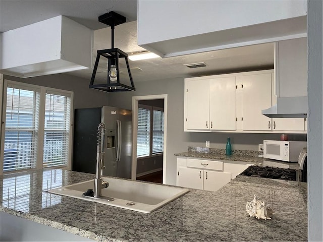 kitchen featuring sink, stainless steel appliances, light stone countertops, white cabinets, and kitchen peninsula