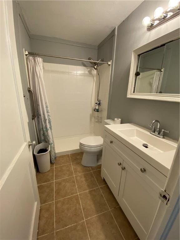 bathroom featuring tile patterned flooring, vanity, toilet, and walk in shower