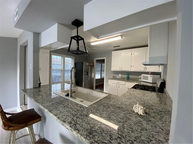 kitchen with stainless steel fridge with ice dispenser, white cabinetry, sink, range, and kitchen peninsula