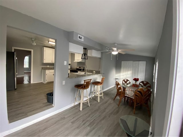 dining room featuring hardwood / wood-style flooring, ceiling fan, sink, and vaulted ceiling