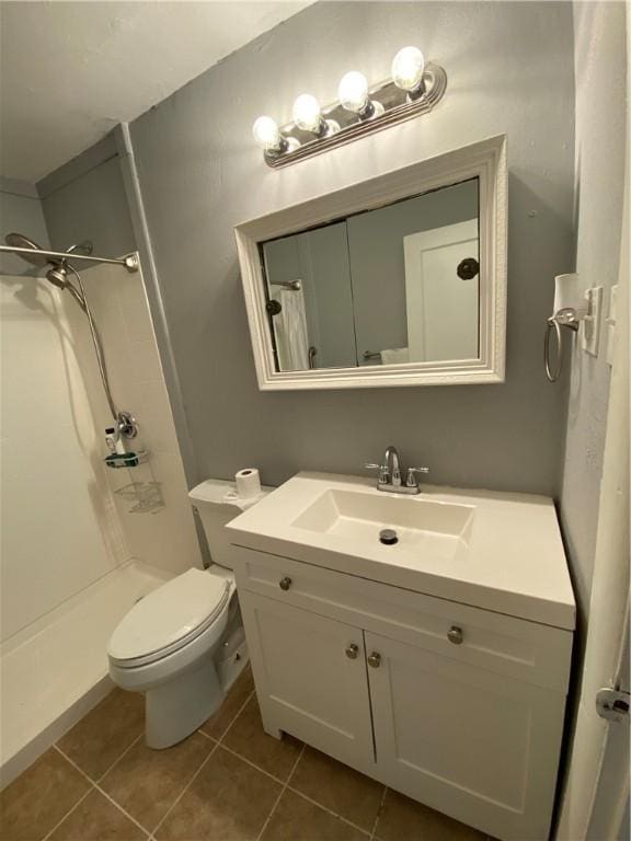 bathroom featuring walk in shower, vanity, toilet, and tile patterned flooring