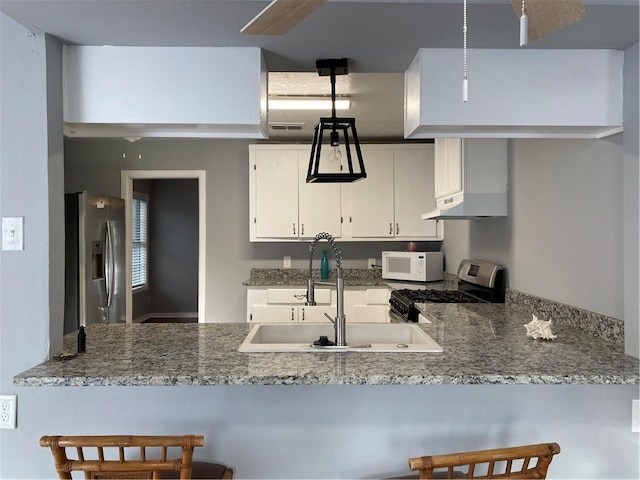 kitchen featuring sink, white cabinetry, light stone counters, appliances with stainless steel finishes, and kitchen peninsula