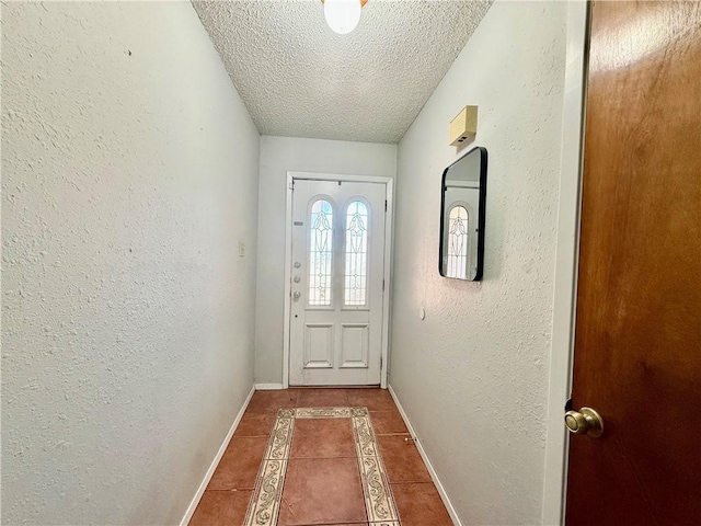 doorway with tile patterned floors, a textured ceiling, baseboards, and a textured wall