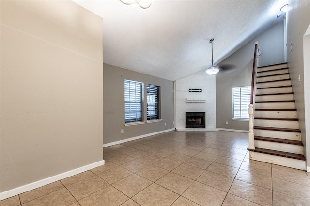 unfurnished living room featuring light tile patterned flooring, a fireplace, stairs, and vaulted ceiling