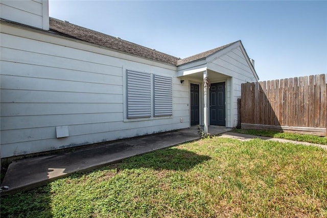 view of front facade with a front lawn, fence, and a shingled roof