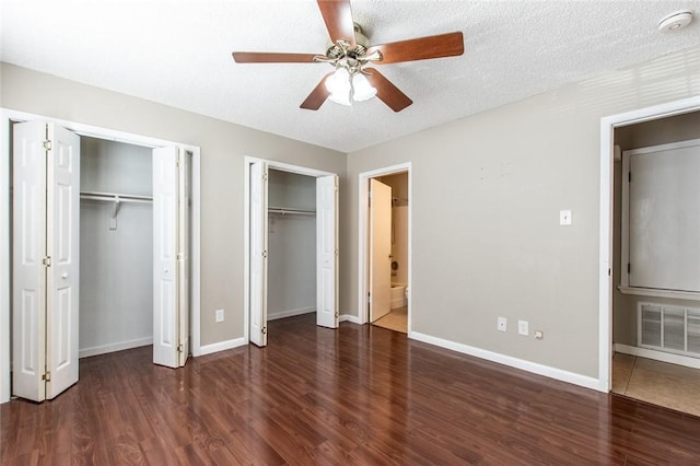 unfurnished bedroom with visible vents, multiple closets, baseboards, and wood finished floors