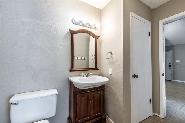 bathroom featuring tile patterned floors, toilet, vanity, and baseboards