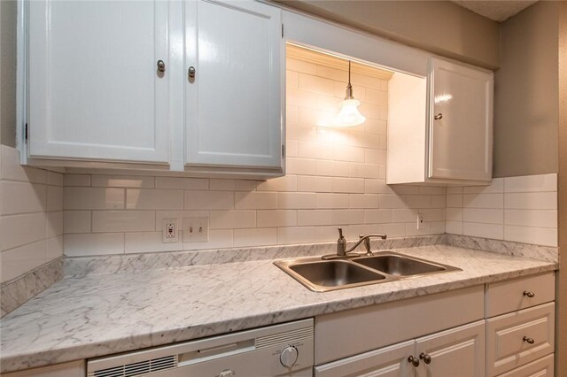 kitchen with dishwasher, light countertops, white cabinets, and a sink