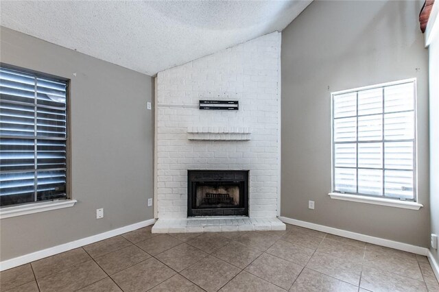 unfurnished living room featuring baseboards, a fireplace, tile patterned flooring, vaulted ceiling, and a textured ceiling