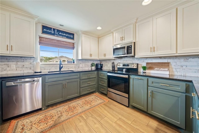 kitchen with white cabinetry, sink, stainless steel appliances, and light hardwood / wood-style floors