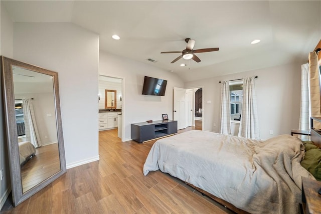 bedroom featuring ensuite bath, ceiling fan, light hardwood / wood-style flooring, and vaulted ceiling