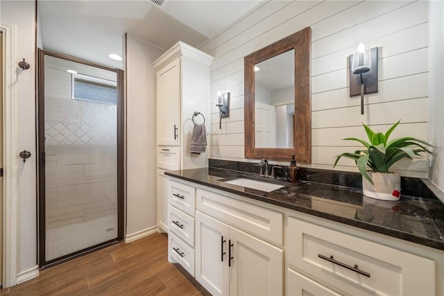 bathroom with vanity, hardwood / wood-style flooring, walk in shower, and wooden walls