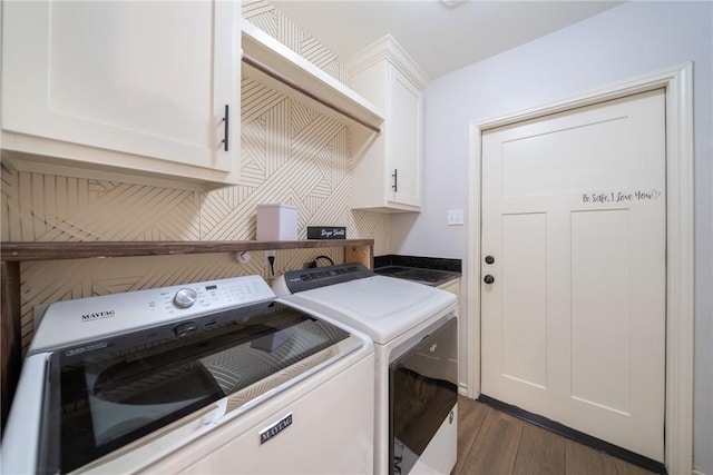 laundry room featuring washing machine and clothes dryer, cabinets, and dark hardwood / wood-style floors