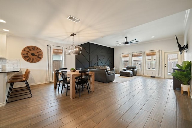 dining room with light hardwood / wood-style flooring and ceiling fan with notable chandelier