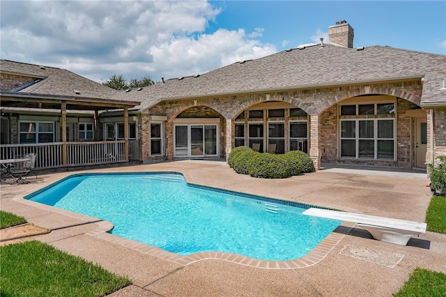 view of swimming pool featuring a diving board and a patio area