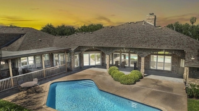 pool at dusk featuring a patio