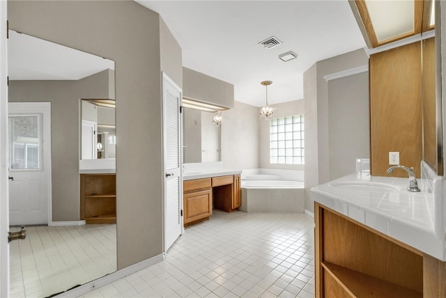 bathroom featuring a relaxing tiled tub, tile patterned floors, an inviting chandelier, and vanity