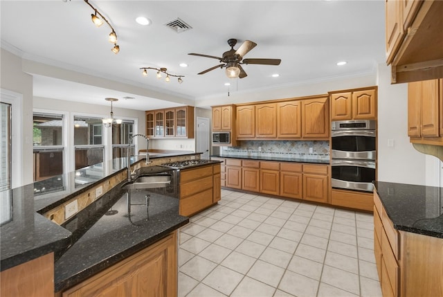 kitchen with ornamental molding, appliances with stainless steel finishes, decorative light fixtures, sink, and dark stone countertops