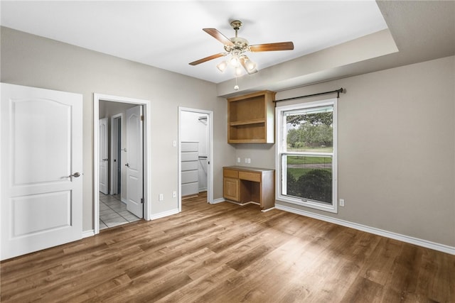 unfurnished bedroom featuring ensuite bath, ceiling fan, a closet, light wood-type flooring, and a spacious closet