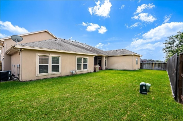 rear view of property with a yard and central air condition unit