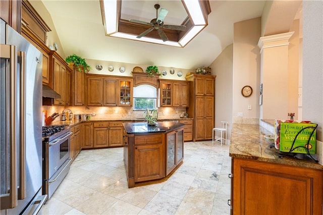 kitchen featuring ceiling fan, appliances with stainless steel finishes, a center island, tasteful backsplash, and ornate columns