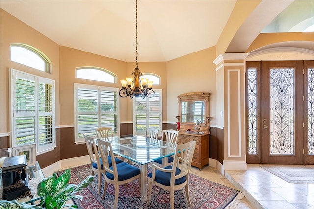 dining room featuring decorative columns, vaulted ceiling, and a notable chandelier