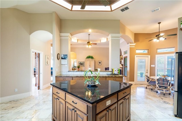 kitchen with stainless steel fridge, ceiling fan, dark stone countertops, a tray ceiling, and kitchen peninsula