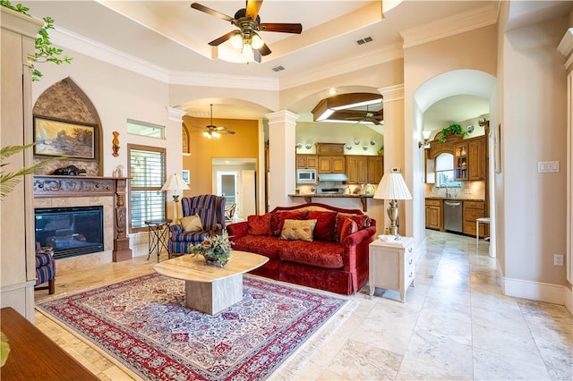 living room with ceiling fan, a premium fireplace, and a tray ceiling