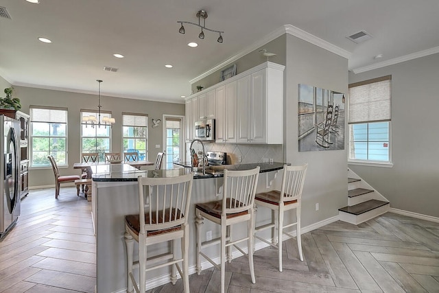 kitchen with visible vents, dark countertops, appliances with stainless steel finishes, a peninsula, and decorative backsplash