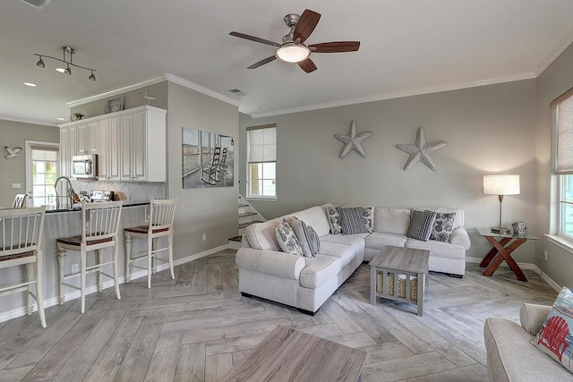 living area featuring visible vents, crown molding, baseboards, stairway, and a ceiling fan